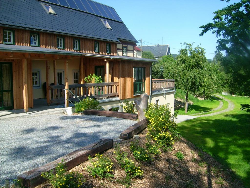 a large wooden house with a porch and a driveway at Ferienhaus "Zur Ottendorfer Hütte" in Ottendorf