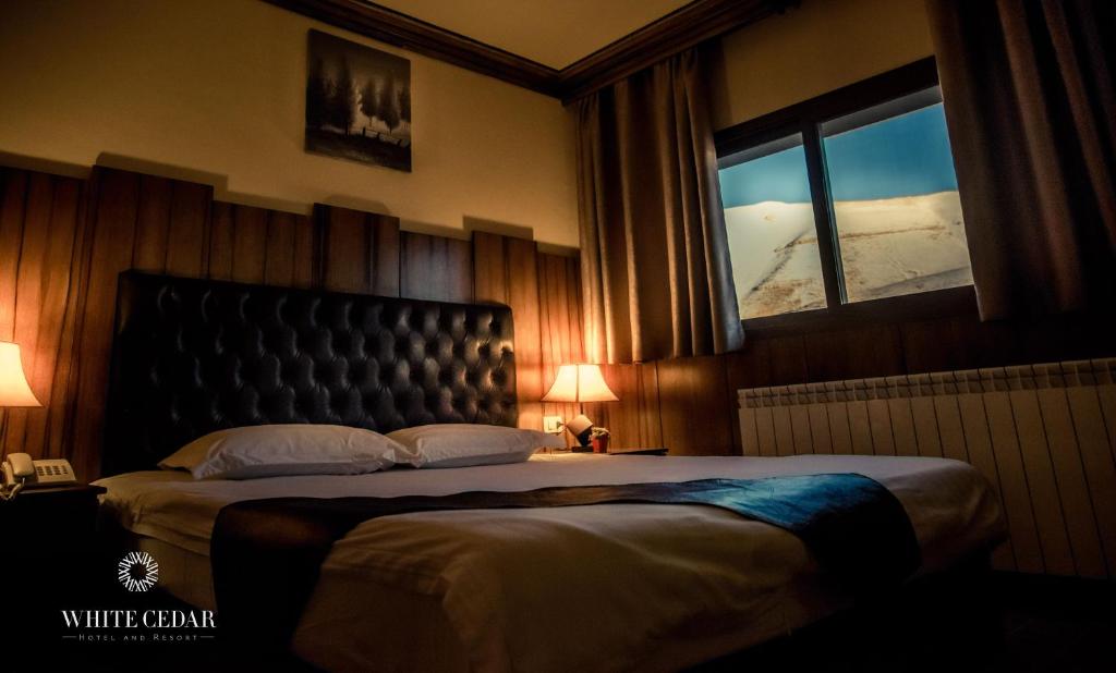 a bedroom with a large bed and a window at White Cedar Hotel &Resort in Al Arz