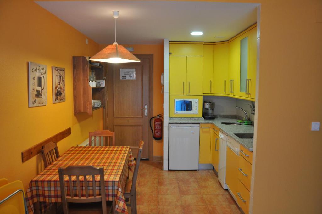 Apartamento en Isaba (NAVARRA) في إيسابا: مطبخ مع دواليب صفراء وطاولة مع مفرش