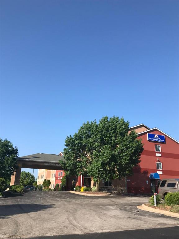 un estacionamiento frente a un edificio con un árbol en Americas Best Value Inn and Suites Saint Charles, en St. Charles