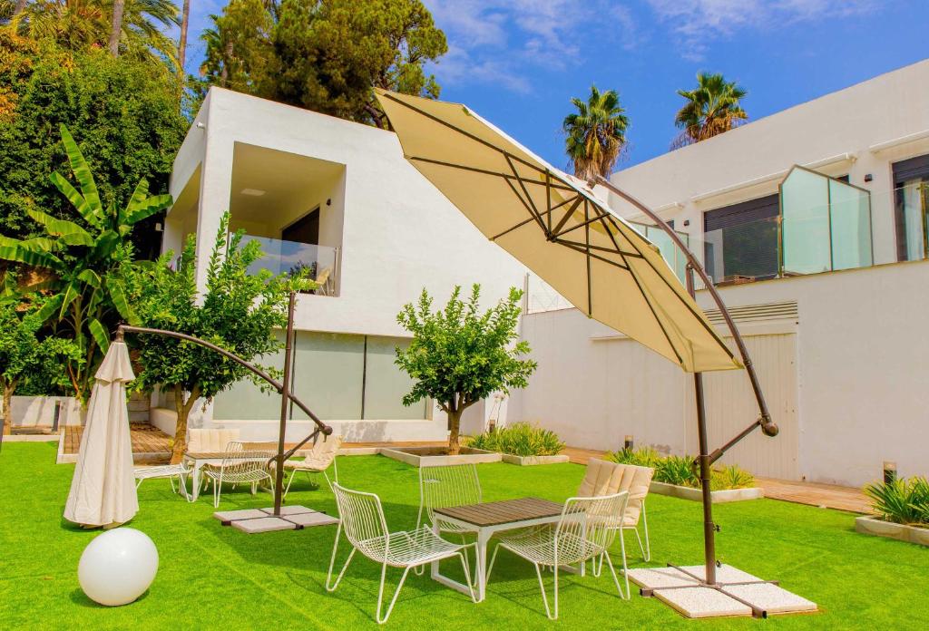 um jardim com cadeiras, uma mesa e um guarda-sol em Dimona Suites Apartamentos Turísticos em Torremolinos