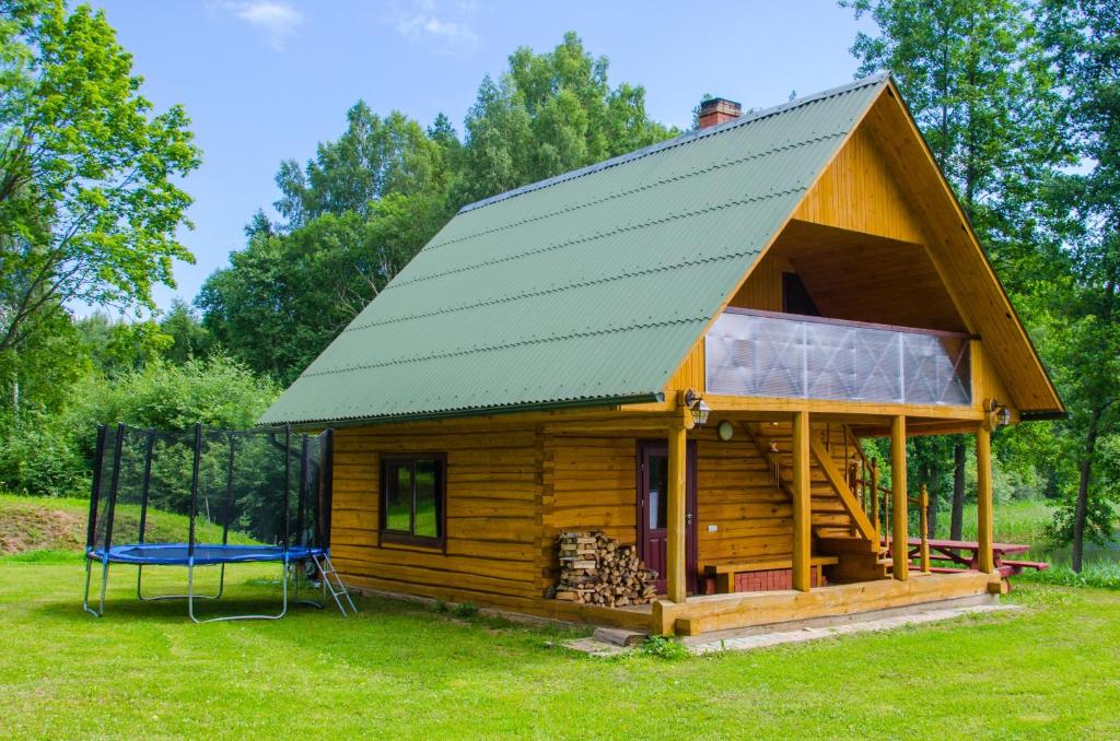 Cabaña de madera con techo verde y columpio en "Čiekuri" en Aglona