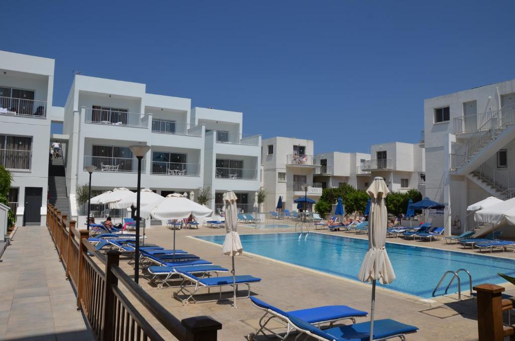 a swimming pool with lounge chairs and umbrellas at Sweet Memories Hotel Apts in Protaras