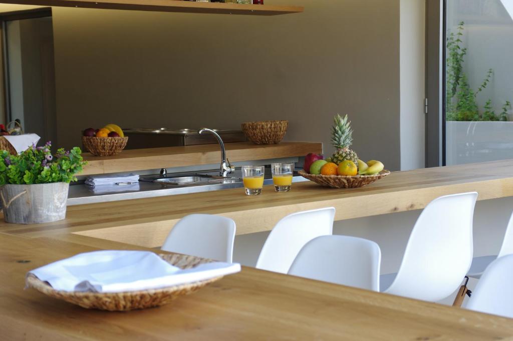 a kitchen with white chairs and a table with fruit on it at Bali Diamond "by Checkin" Adults Only in Bali