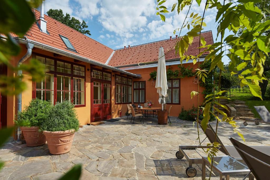 ein Gebäude mit einer Terrasse mit einem Tisch und einem Sonnenschirm in der Unterkunft Villa Tranquillini auf Gut Guntrams in Schwarzau am Steinfelde