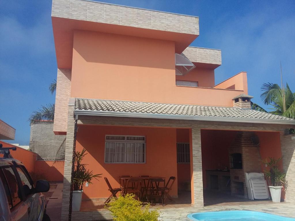 a villa with a pool in front of a house at Conforto Laranja in Ilha Comprida