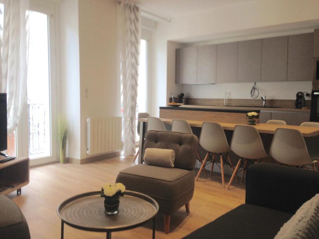 ein Wohnzimmer mit Tisch und Stühlen und eine Küche in der Unterkunft Standing et confort Plein centre pour 8 personnes in Cauterets