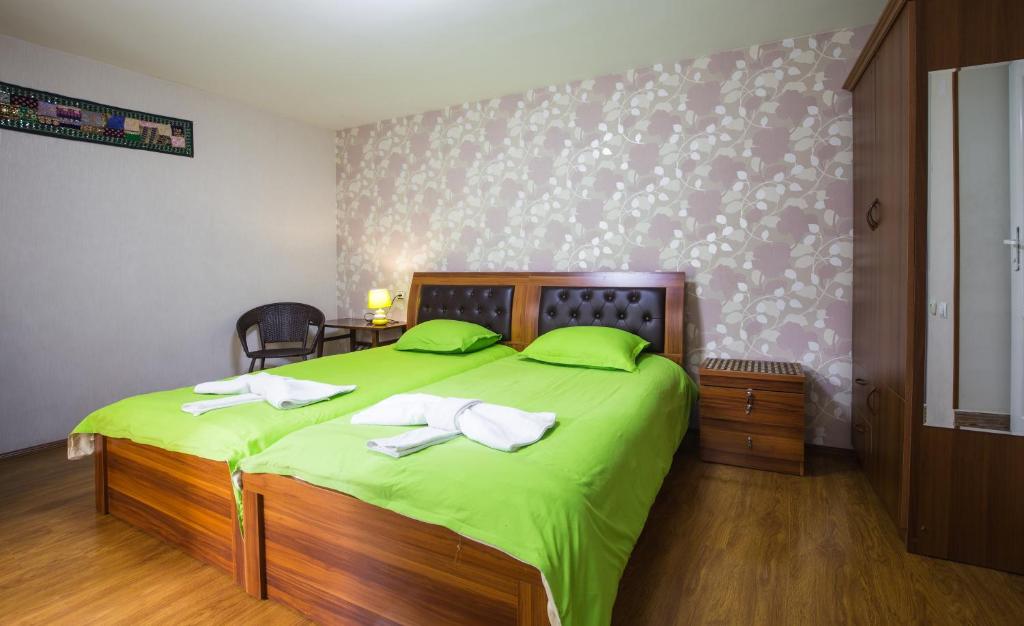 a bedroom with a large green bed with green sheets at Sophie`s Garden in Tbilisi City