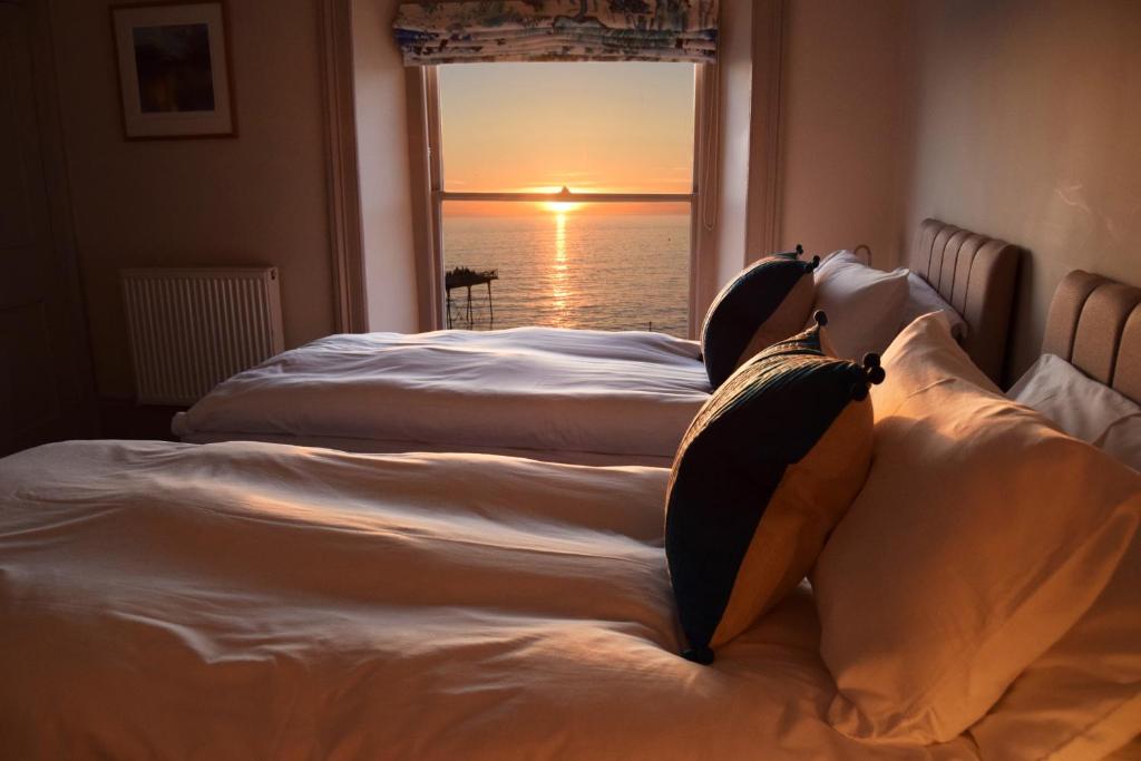 two beds in a room with a view of the ocean at Awel Mor Holiday Apartment in Aberystwyth