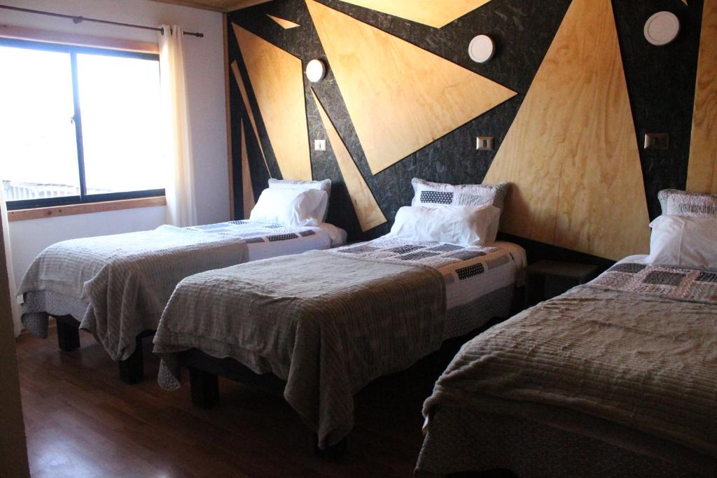 a room with three beds and a large window at Residencial del Maule in Linares