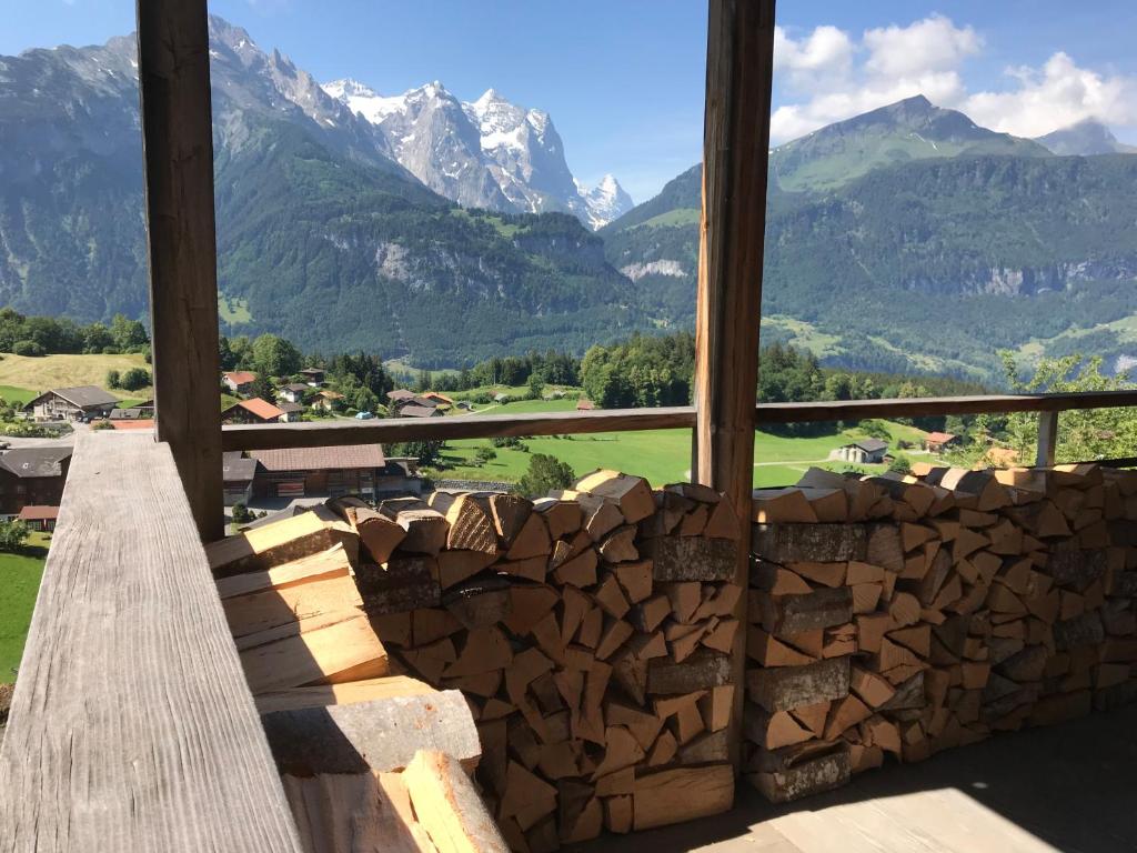 una pila de troncos frente a una ventana con montañas en Alp n' rose en Hasliberg