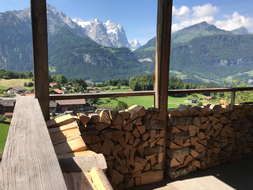 a pile of logs in front of a window with mountains at Alp n' rose in Hasliberg