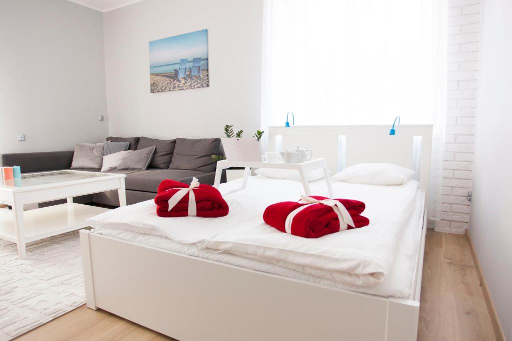 a white room with a bed with red pillows on it at Studio Morski Klimat in Władysławowo