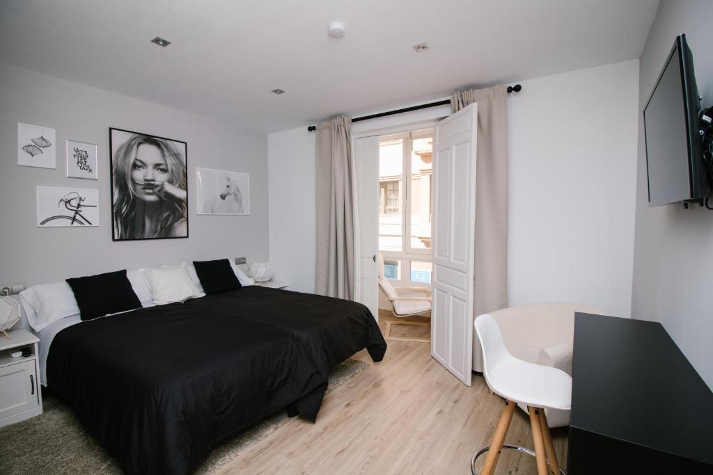 a bedroom with a black bed and a desk and a window at Infinium Zamora Suites in Zamora