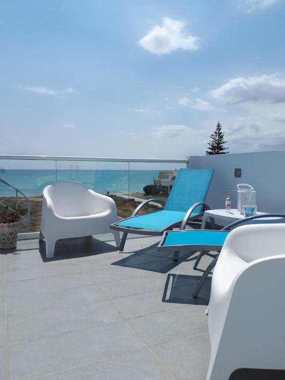 a group of chairs and tables on a patio with the ocean at Cozy beach house in Pervolia