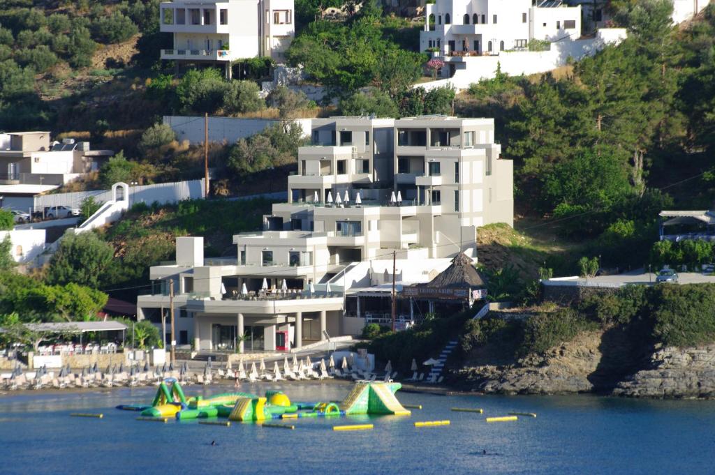 a large white building on a hill with boats in the water at Bali Diamond "by Checkin" Adults Only in Bali