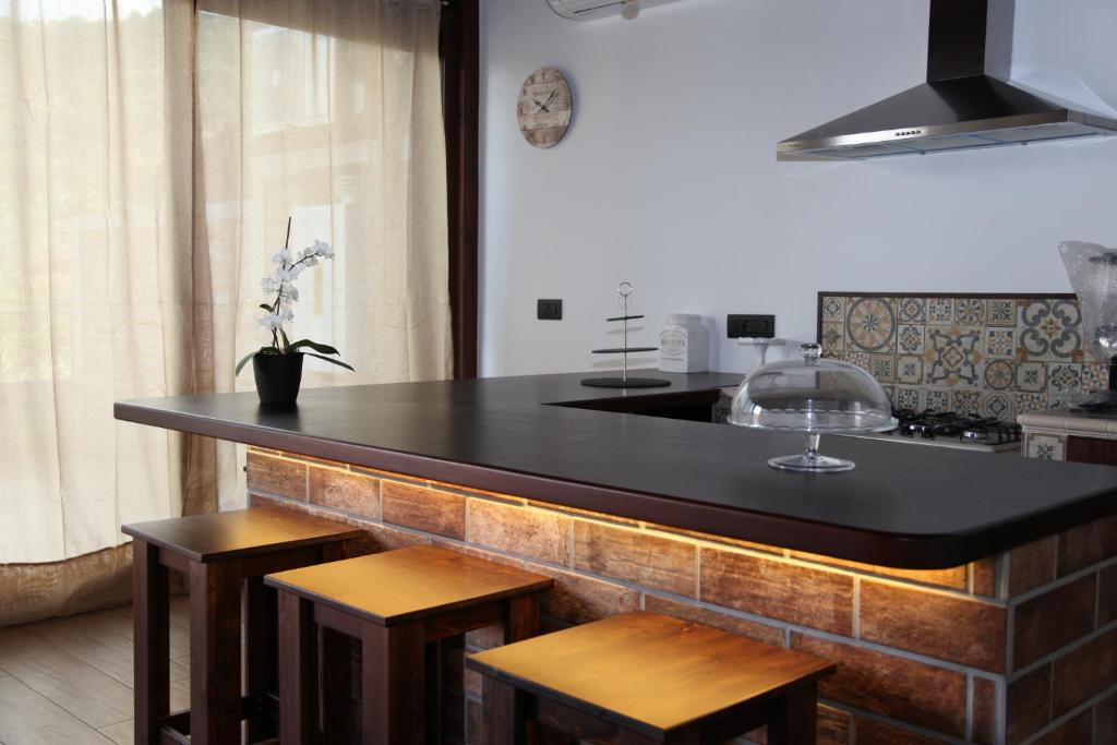 a kitchen with a black counter and some stools at Ermes B&B in Falcone
