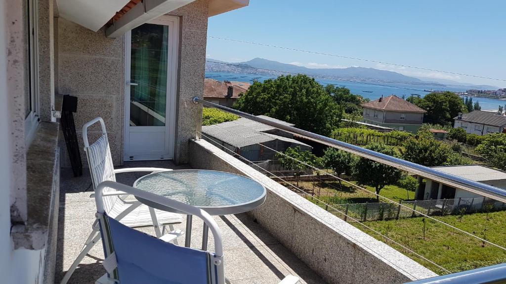 a glass table and chairs on a balcony with a view at Apartamento con estupendas vistas in Moaña