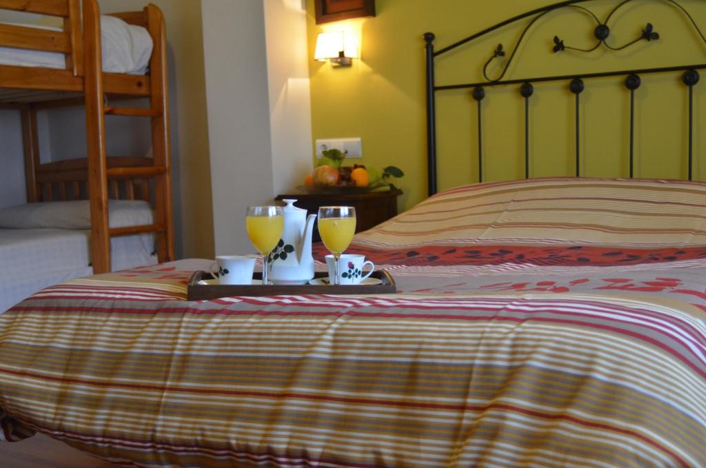 a bedroom with a bed with two glasses of orange juice at Hostal Rural El Padul in Padul