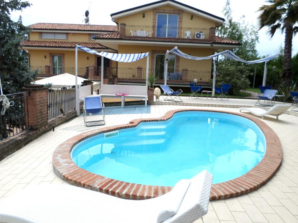 a swimming pool with two chairs and a house at Bed and Breakfast Villa Algi in Corropoli