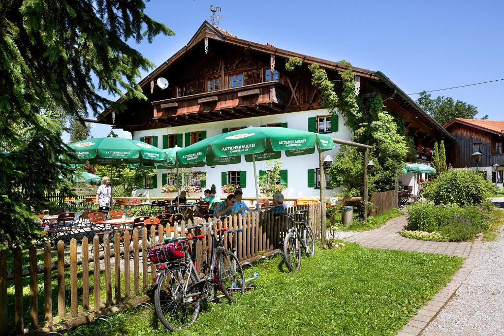 a building with green umbrellas and bikes parked next to a fence at Landhotel Huberhof in Schwangau