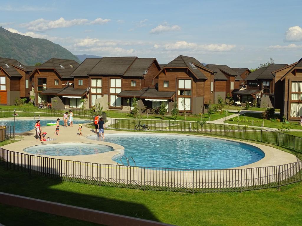 un groupe de personnes jouant dans une piscine avec des maisons dans l'établissement Departamento en Pucon, à Pucón