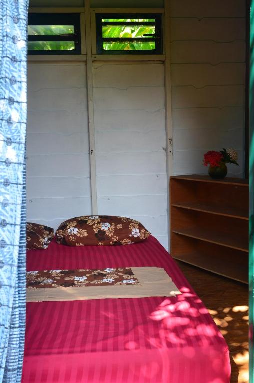 a bed in a room with two windows at Fare Om in Pihaena