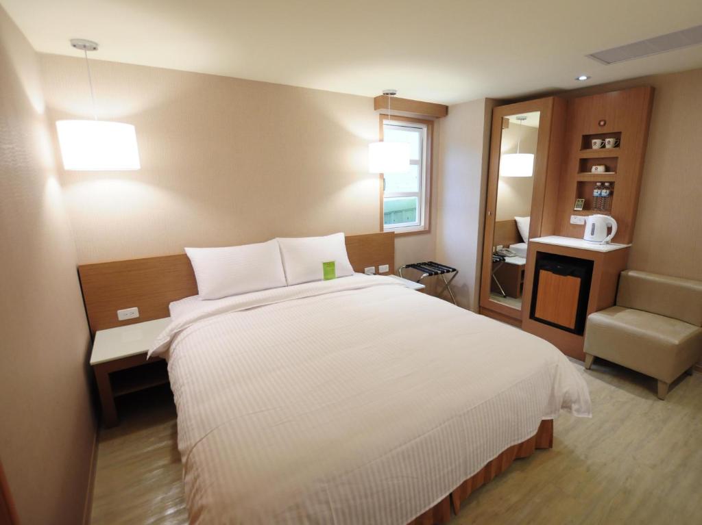 a bedroom with a large white bed and a chair at Kindness Hotel - Tainan Chihkan Tower in Tainan