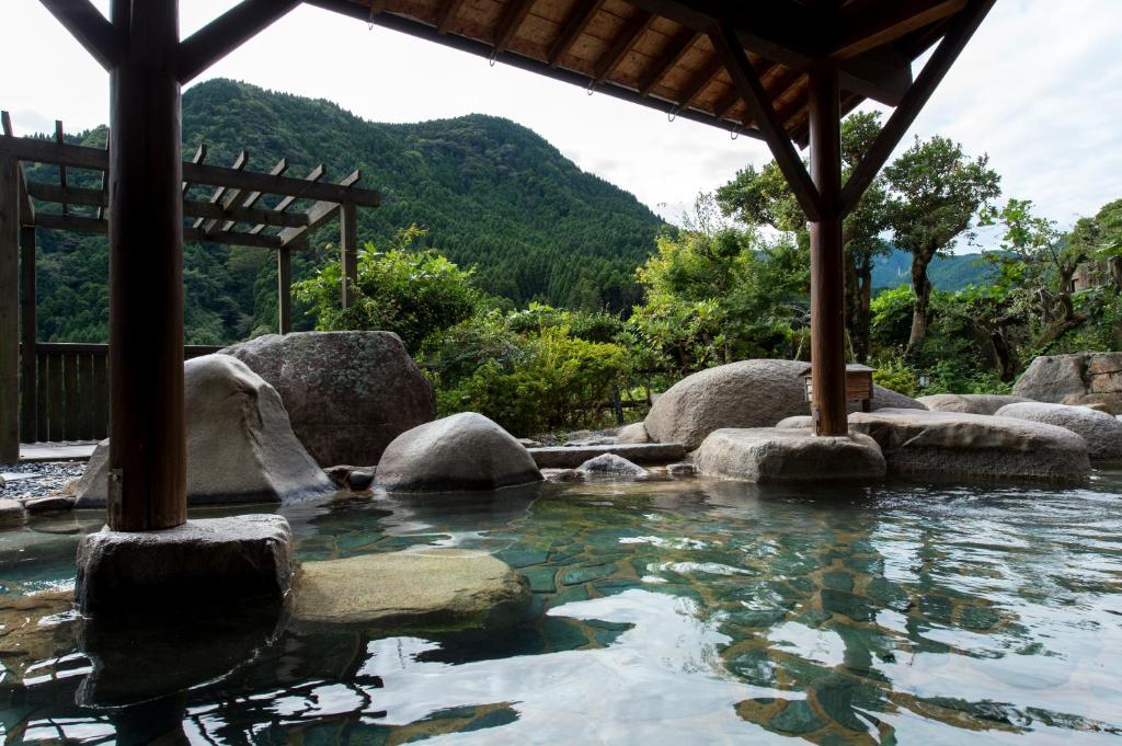 a pool of water with rocks and a gazebo at Furuyu Onsen Oncri in Saga