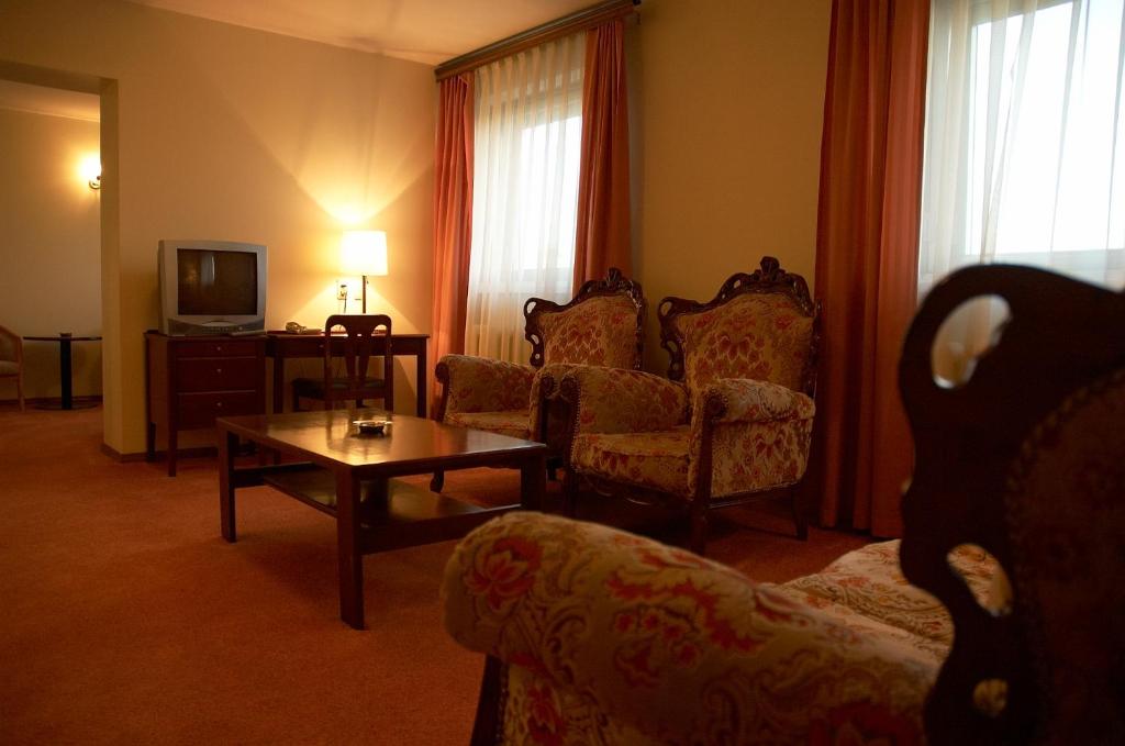 a living room with a couch and a table and a tv at Sakhalin Sapporo Hotel in Yuzhno-Sakhalinsk