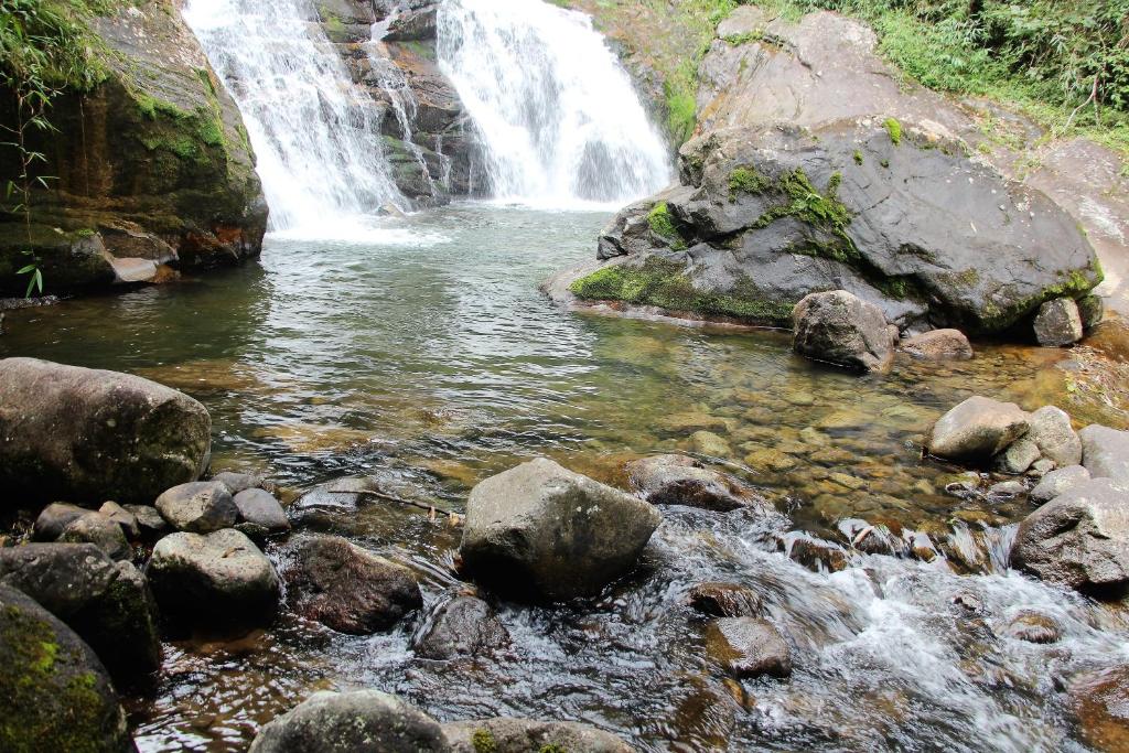 a waterfall in front of a river with rocks at Refúgio nas Montanhas in Engenheiro Passos