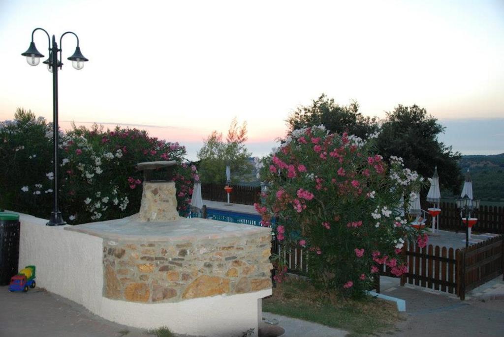 uma fonte de pedra num quintal com flores cor-de-rosa em Agriturismo Le Rondini Di San Bartolo em San Vincenzo