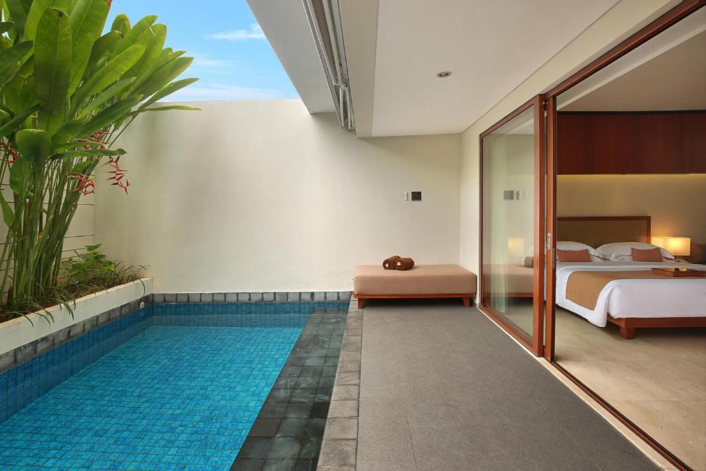 a hotel room with a swimming pool and a bedroom at The Magani Hotel and Spa in Legian