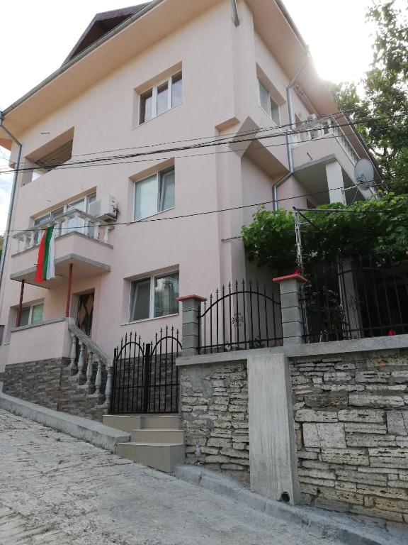 a white house with a fence and a stone wall at Guest House Emi in Balchik