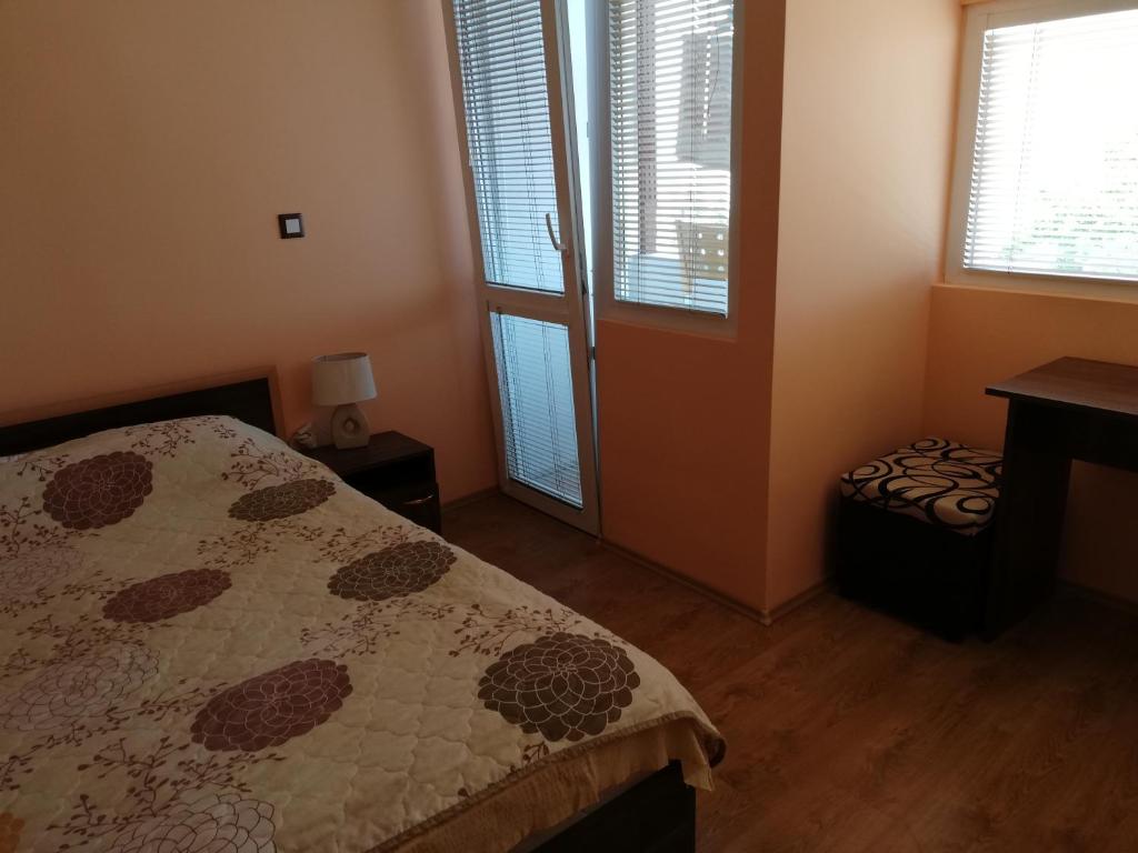 a bedroom with a bed and a table and windows at Guest House Emi in Balchik