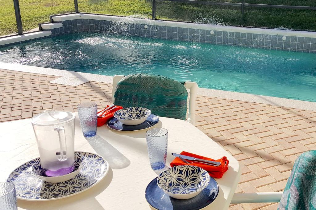 a table with plates of food on it next to a swimming pool at Key 2 Indian Creek Pool Home in Kissimmee