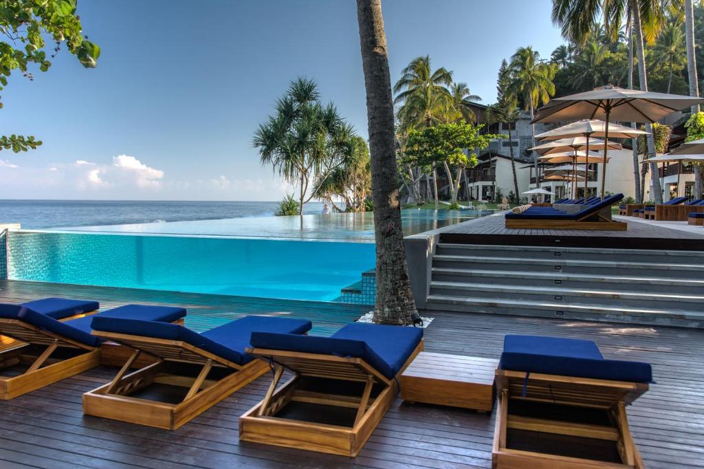 a swimming pool with lounge chairs and the ocean at Katamaran Hotel & Resort in Senggigi 