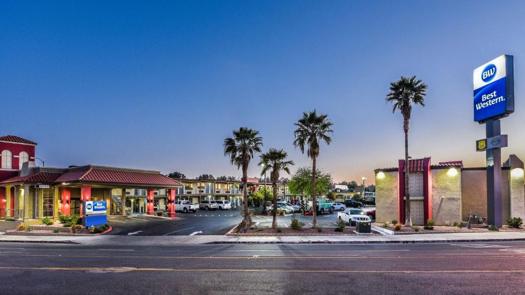 una calle vacía con una gasolinera y palmeras en Best Western Desert Villa Inn, en Barstow