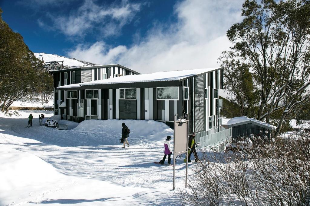 a house in the snow with people in front of it at Elk at Falls in Falls Creek