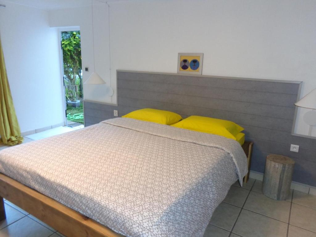 1 dormitorio con 1 cama grande con almohadas amarillas en La Villa Pitaya en LʼEntre-Deux