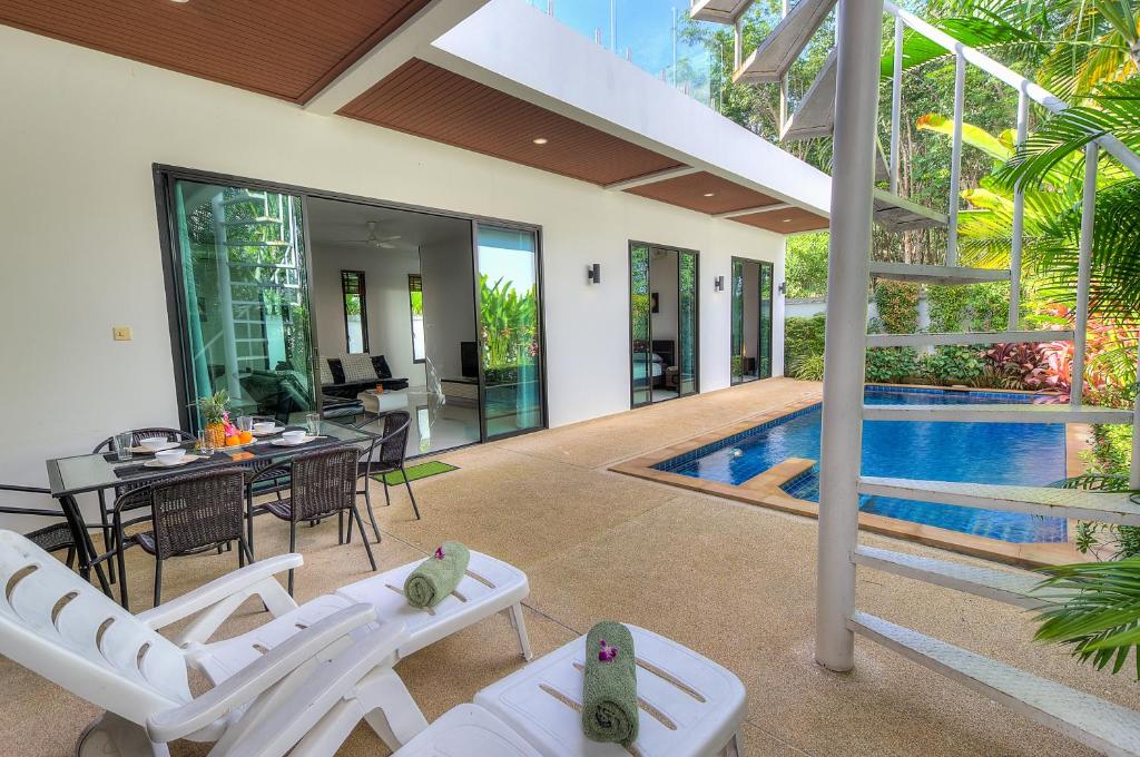 eine Villa mit einem Pool und einer Terrasse mit weißen Stühlen in der Unterkunft Modern 3br Boutique Pool Villa by Intira Villas in Rawai Beach