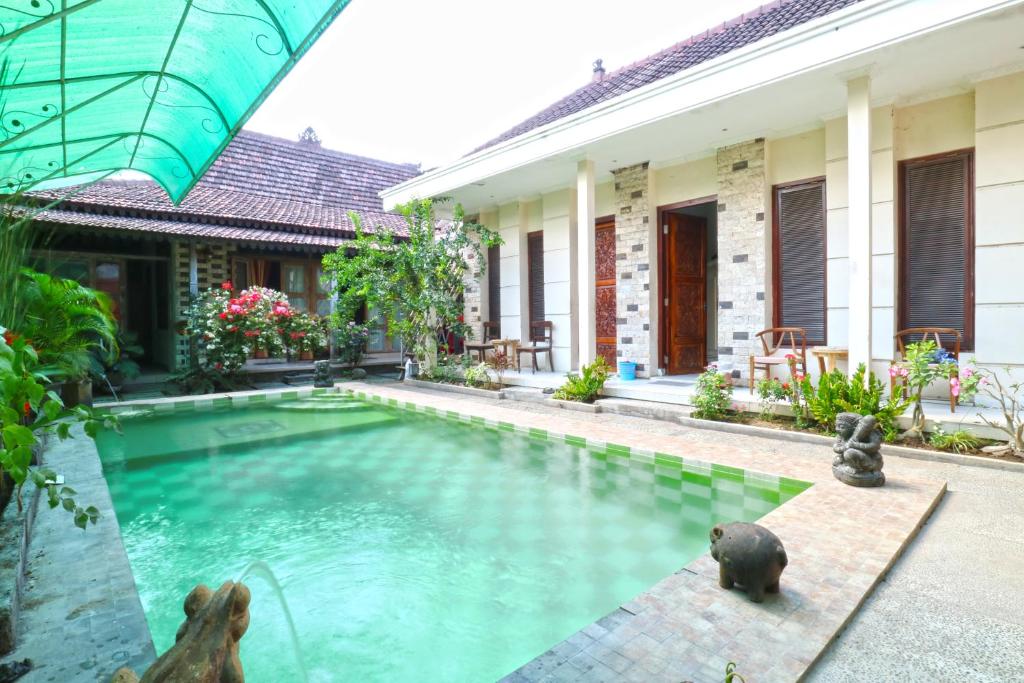 a swimming pool in front of a villa at OYO 90363 Nira Guest House Sanur Bali in Sanur