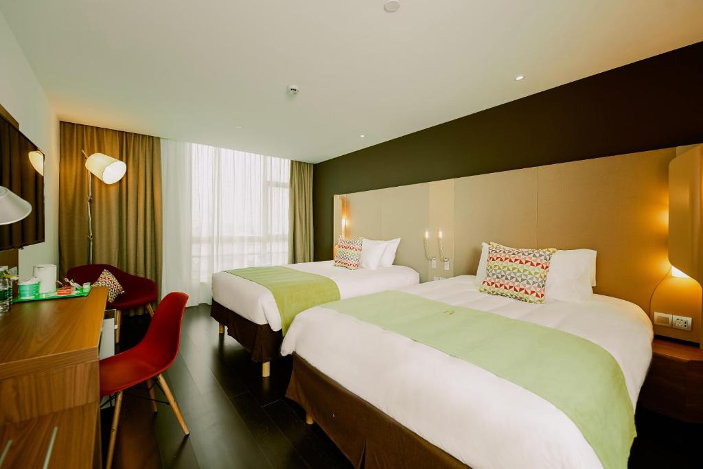 a hotel room with two beds and a desk at Campanile Nanjing Jiangning in Nanjing