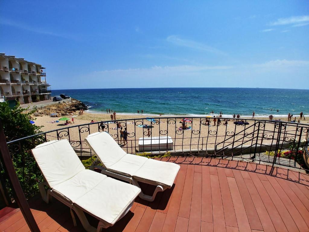 2 sillas blancas sentadas en un balcón con vistas a la playa en Котеджі на приватному пляжу - Совіньон 2024 en Odesa