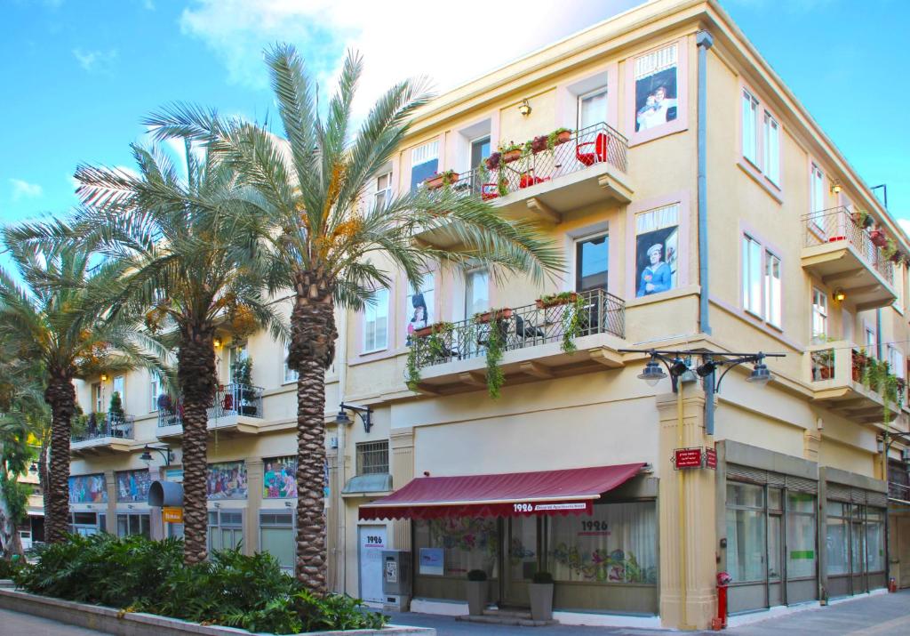 um edifício com palmeiras em frente em 1926 Designed ApartHotel em Haifa