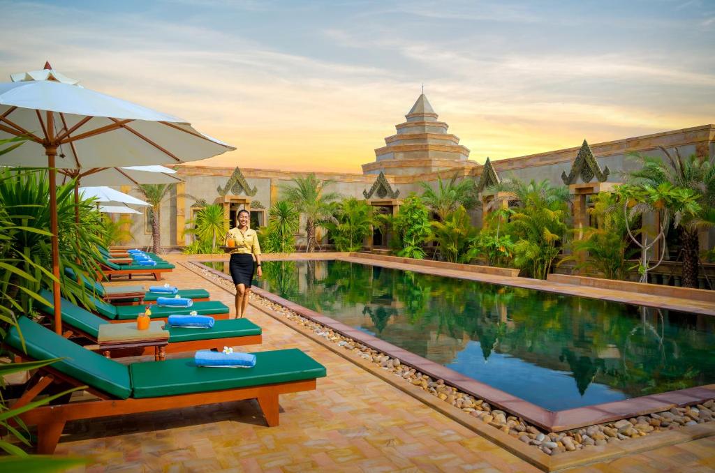 una mujer caminando por una piscina en un resort en Model Temple Villa, en Siem Reap
