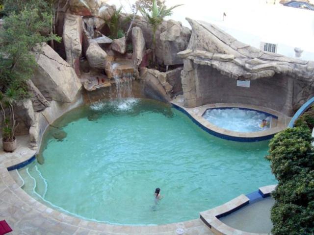 a pool with a waterfall and a person in the water at Beachfront Mooloolaba Apartment- 7th Floor Landmark resort in Mooloolaba