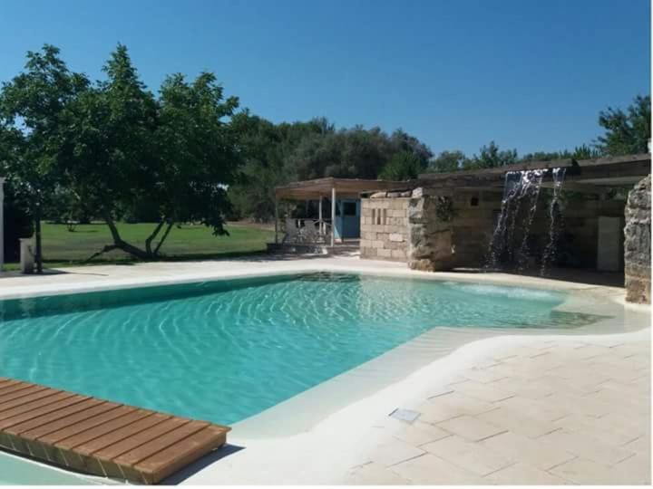 a swimming pool with a waterfall and a water feature at Le Pentume in Arnesano