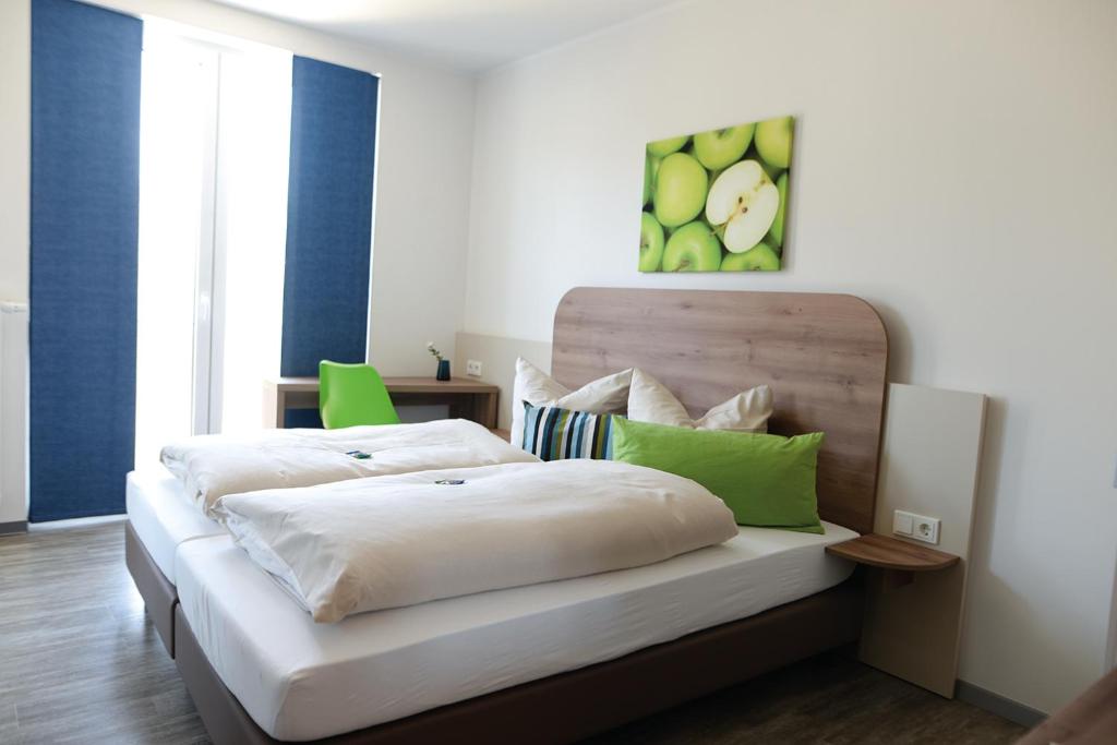 1 Schlafzimmer mit 2 Betten mit grünen Akzenten in der Unterkunft Hotel M24 - Alle Zimmer mit Küchenzeile in Vechta