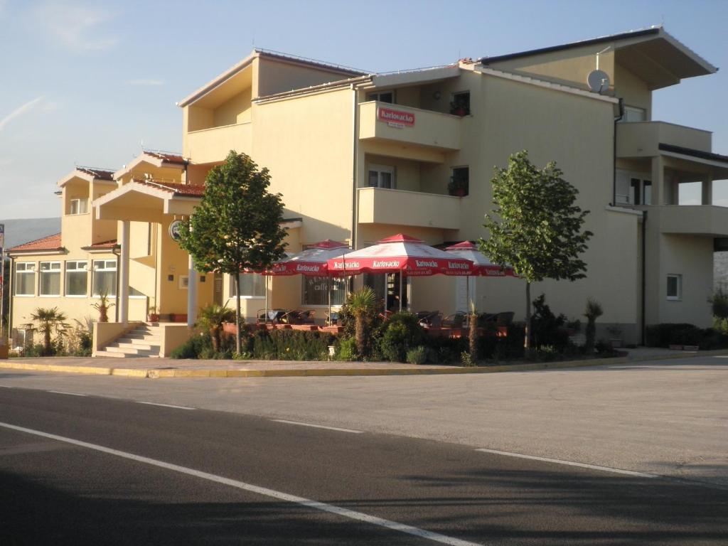 a building with tables and umbrellas next to a street at Motel Janković in Hrvace